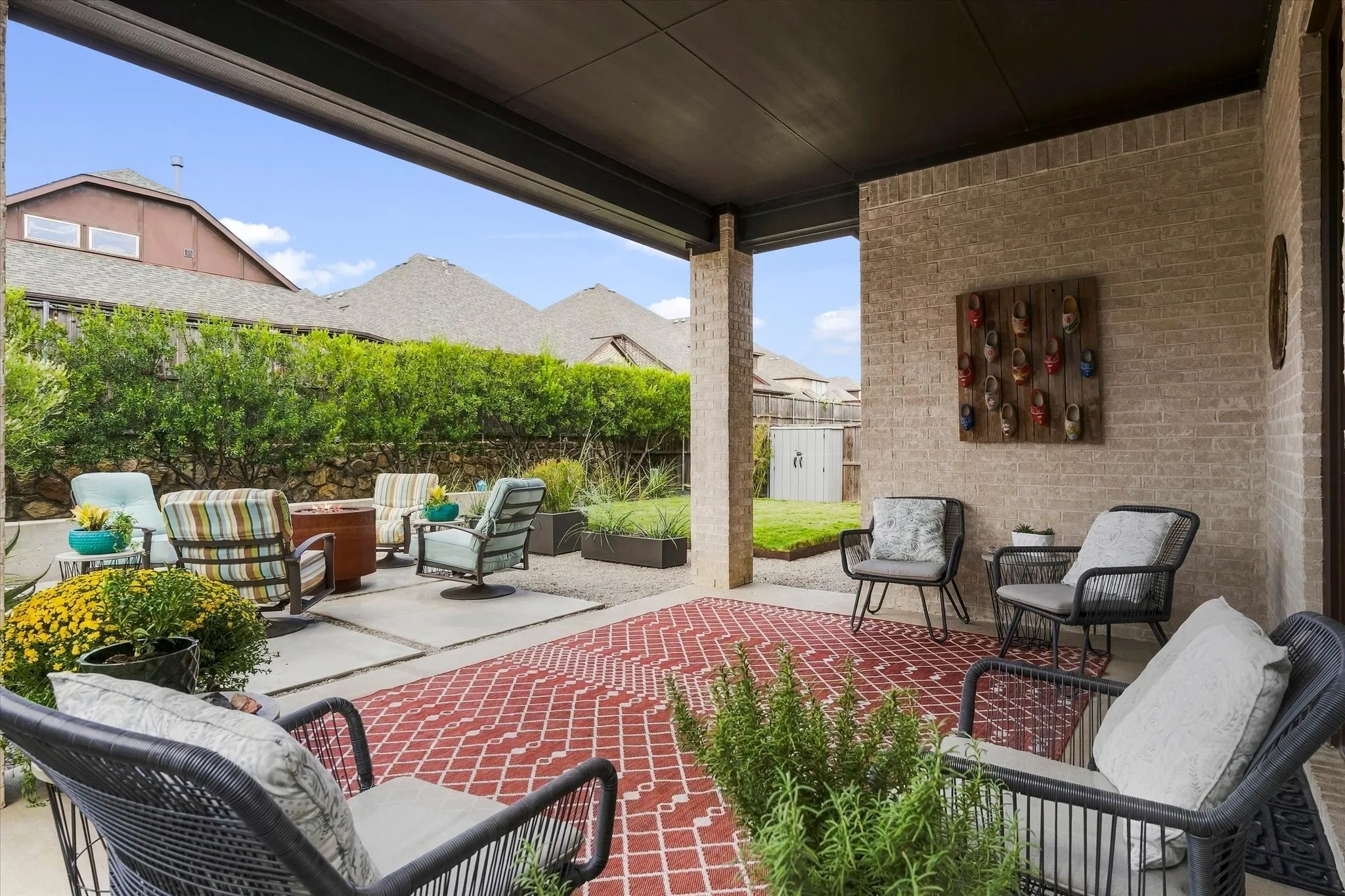 Covered patio with brick wall and concrete columns, featuring a red geometric pattern outdoor rug