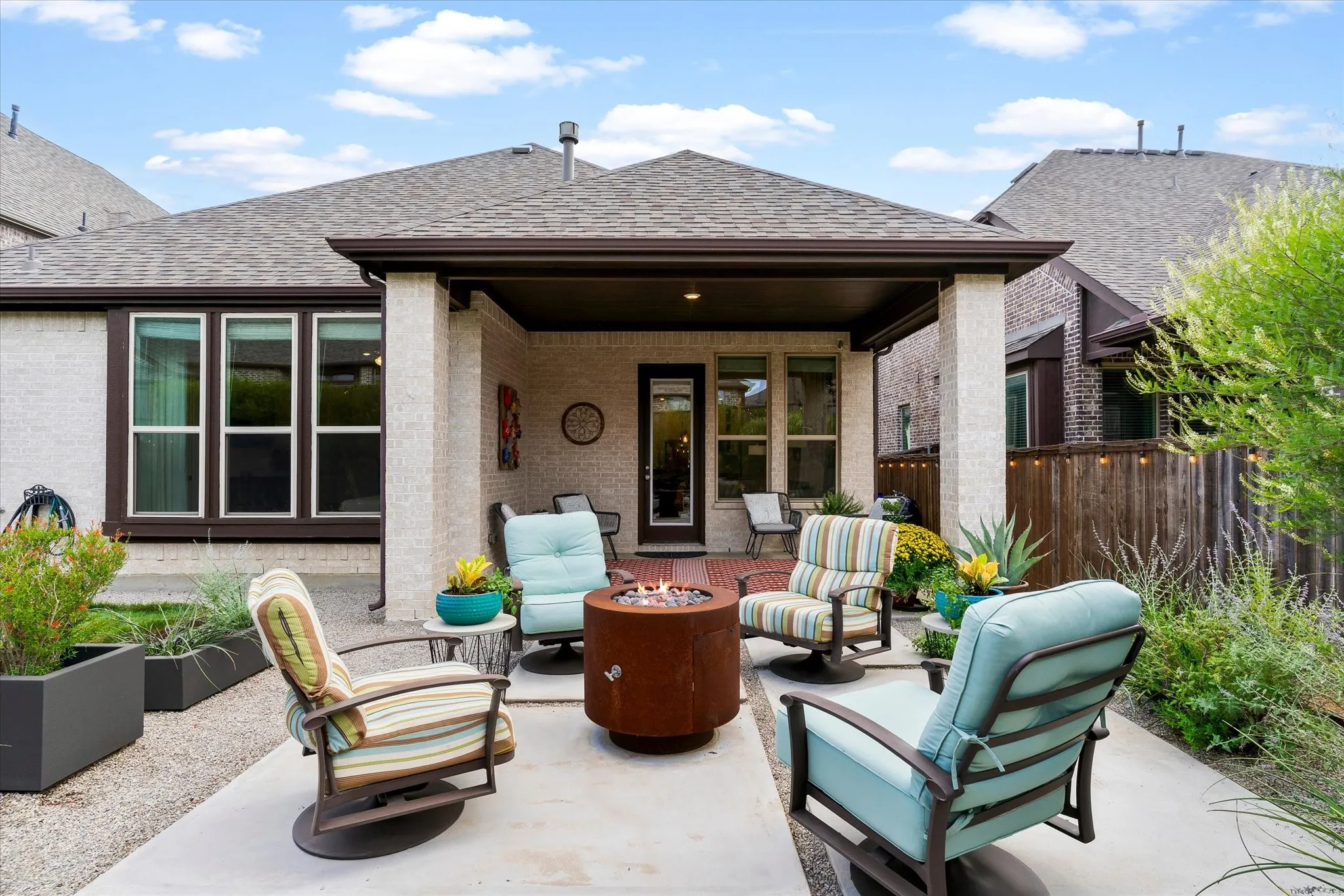Covered patio with a concrete slab, white brick exterior, and a built-in fire pit feature