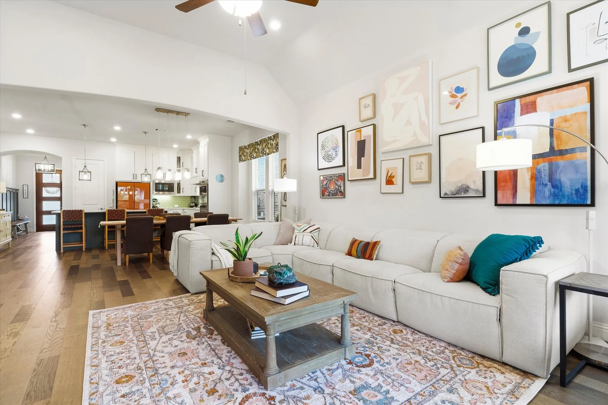Vaulted ceiling with a ceiling fan, recessed lighting, and wood-finish flooring throughout the open-concept living and dining areas