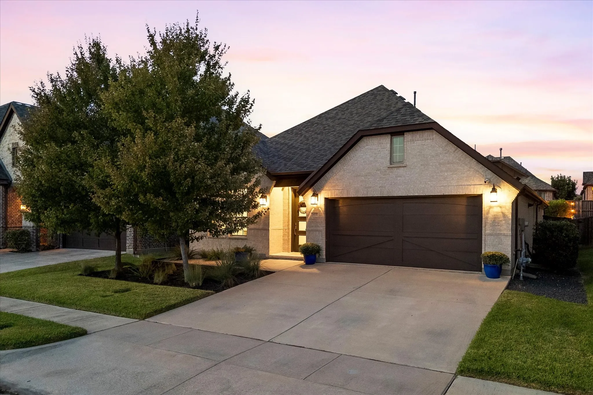 Exterior featuring a concrete driveway, attached garage, stone facade, and mature landscaping