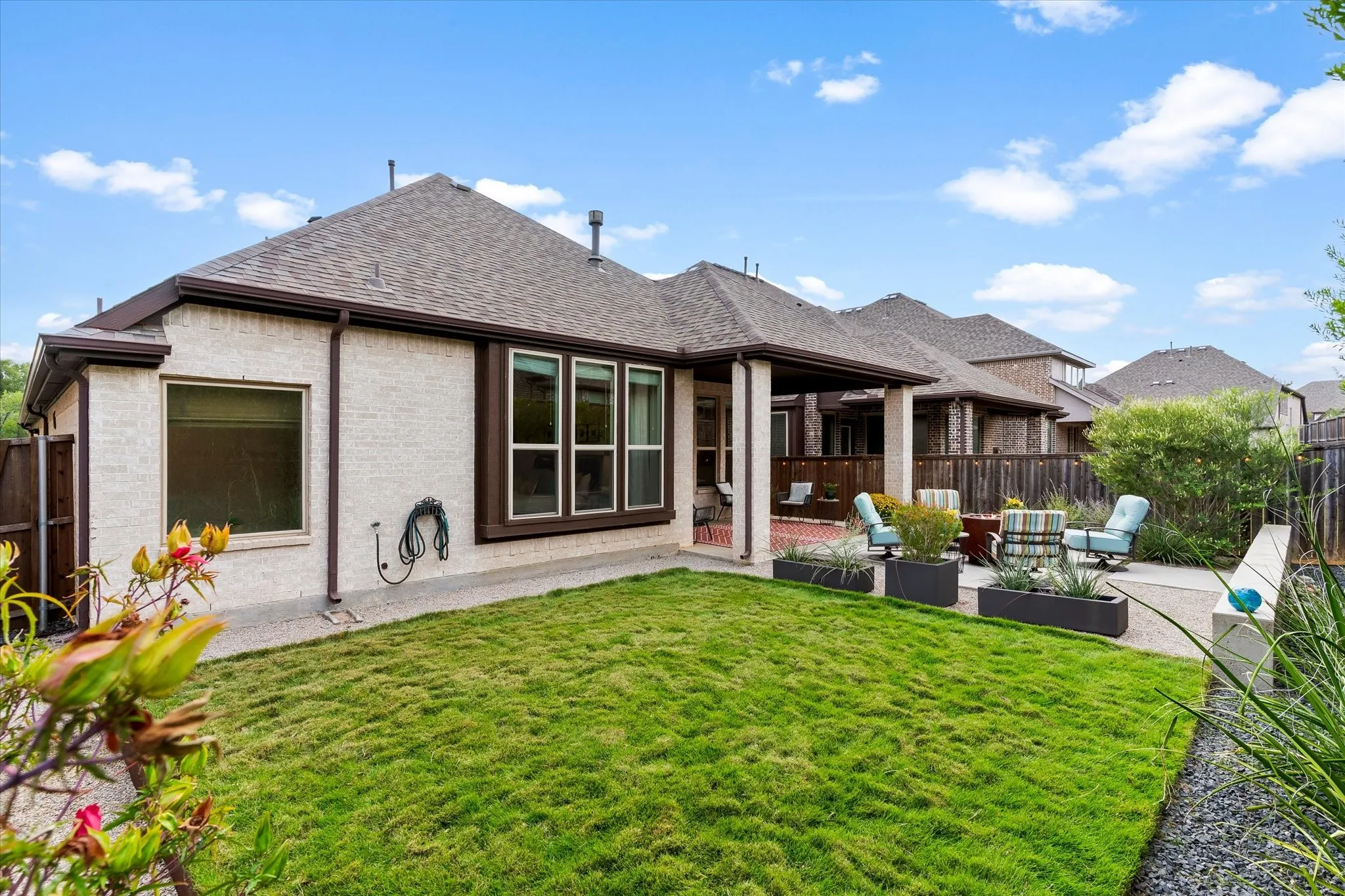 Expansive backyard featuring a green lawn, covered patio, and a stone patio