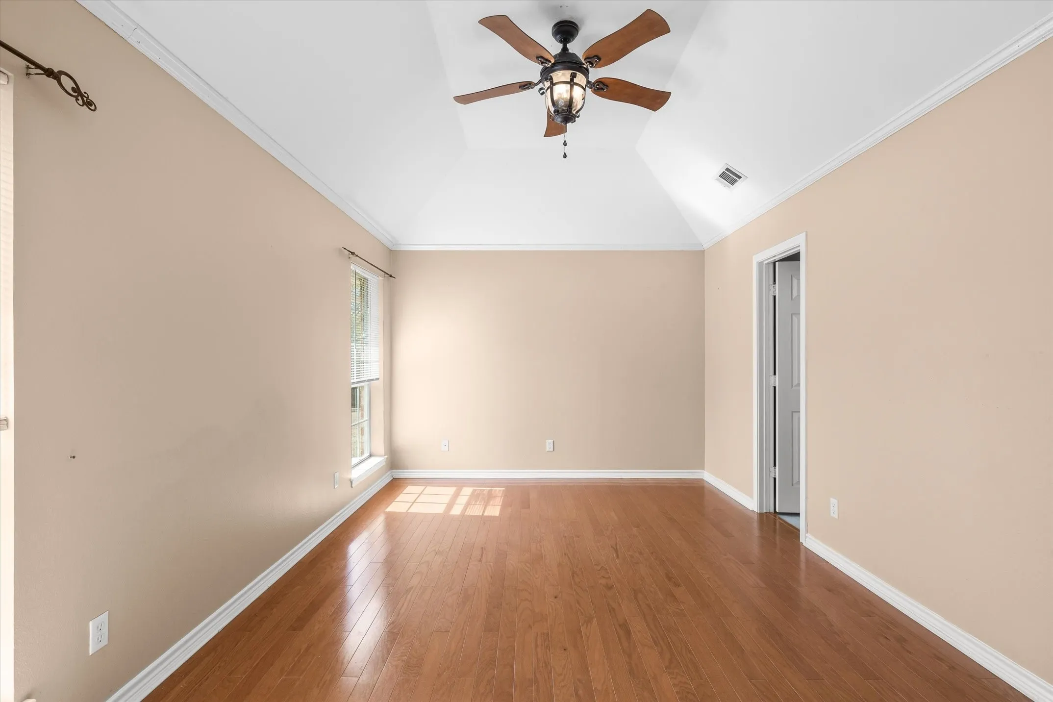 Primary bedroom with tray ceilings and wood floors