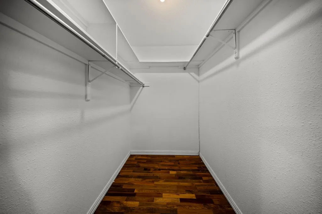 Walk-in closet with wood-finish flooring and integrated shelving