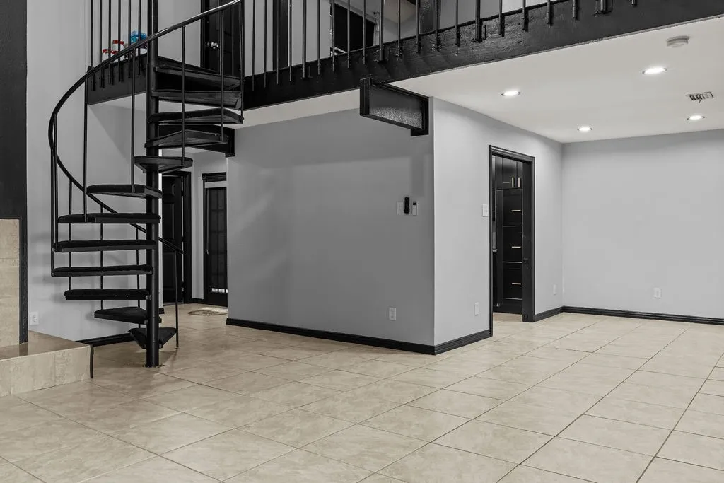 Black spiral staircase, recessed lighting, tile flooring, and dark trim