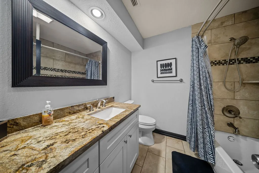 Vanity with stone countertop, undermount sink, and brushed nickel faucet