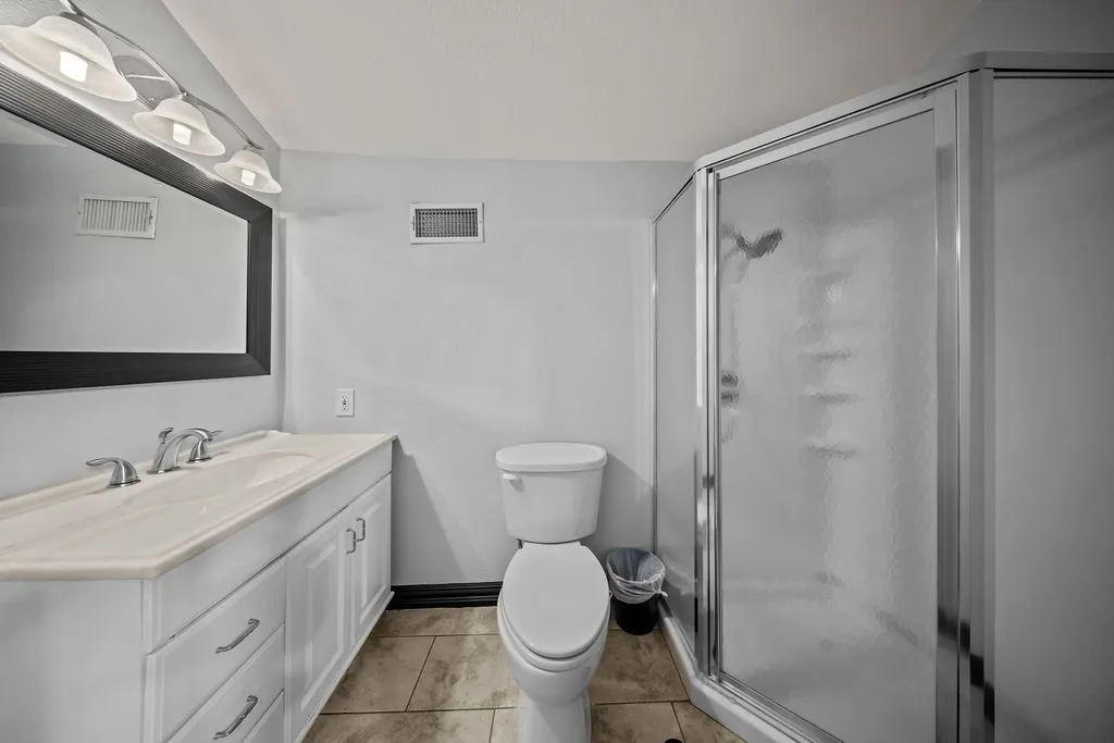 White vanity with integrated sink, chrome faucet, framed mirror, and tiled flooring