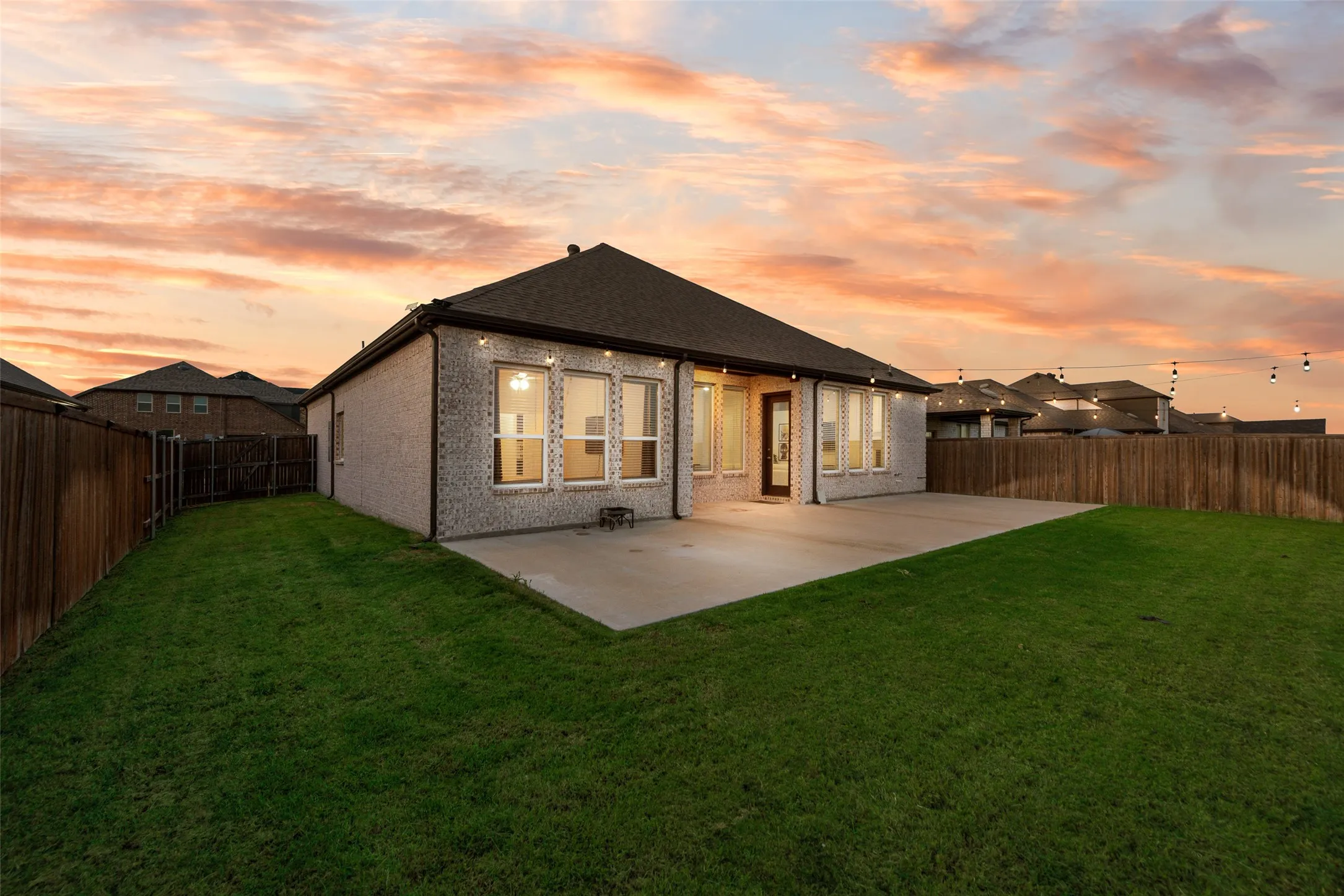 Expansive backyard featuring a manicured lawn, concrete patio, and privacy fencing