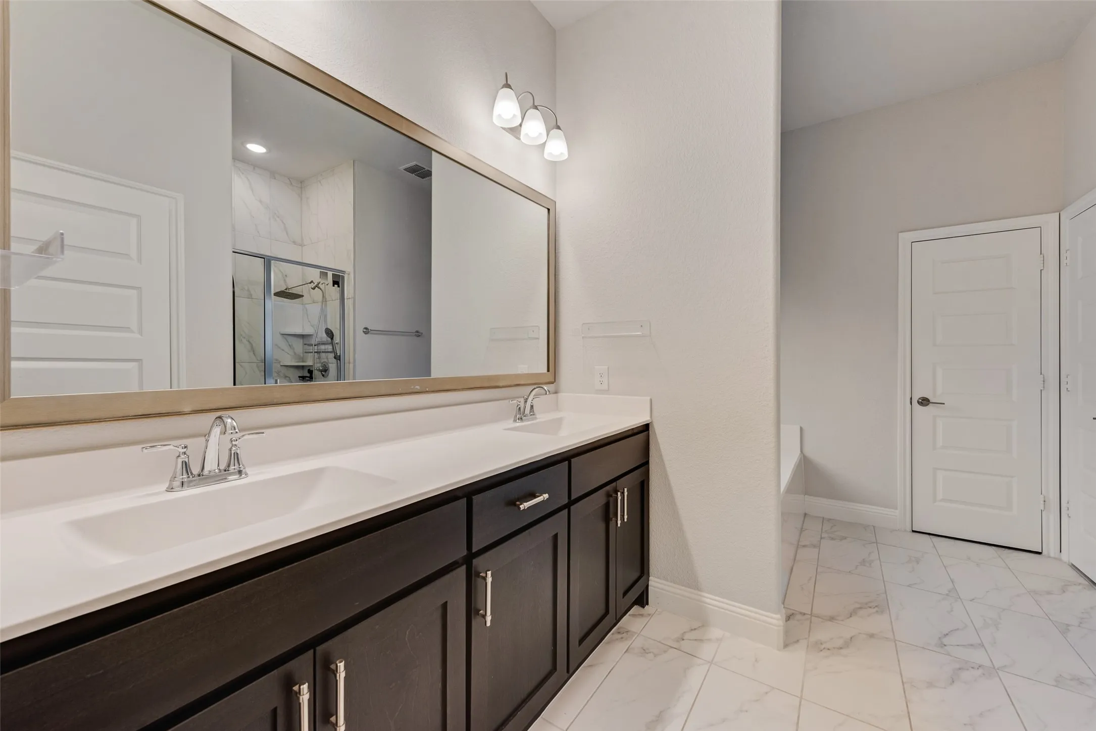 Double vanity featuring integrated sinks, dark wood-finish cabinetry, and chrome fixtures