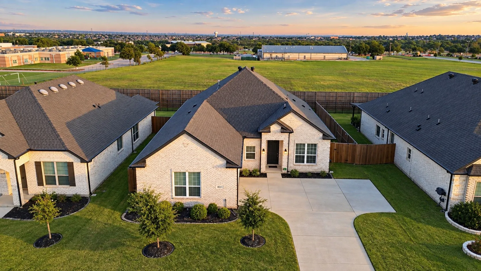 Light brick exterior with dark trim and a dark asphalt shingle roof
