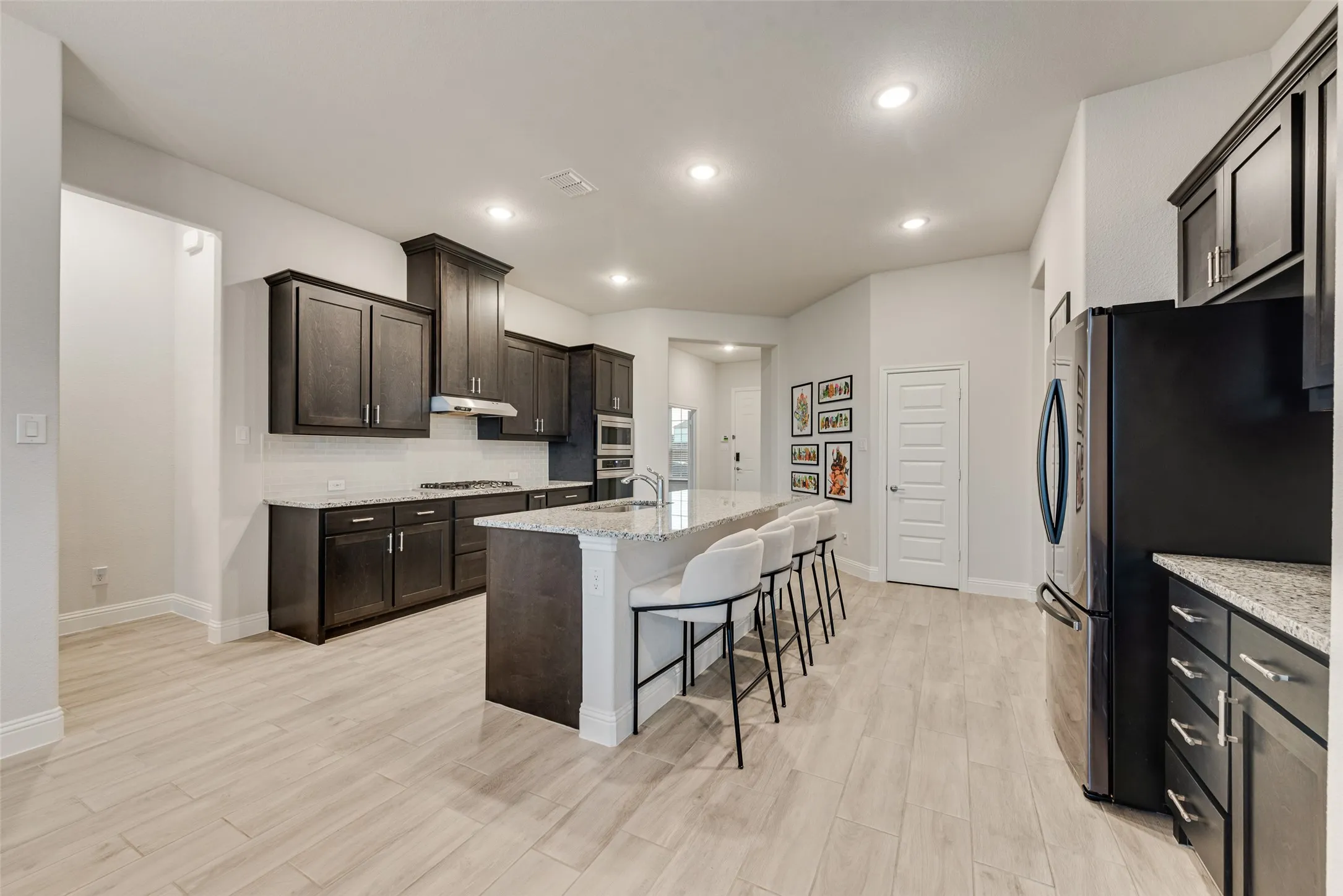 Spacious kitchen featuring dark wood cabinetry, light-colored countertops, stainless steel appliances, and wood-finish flooring