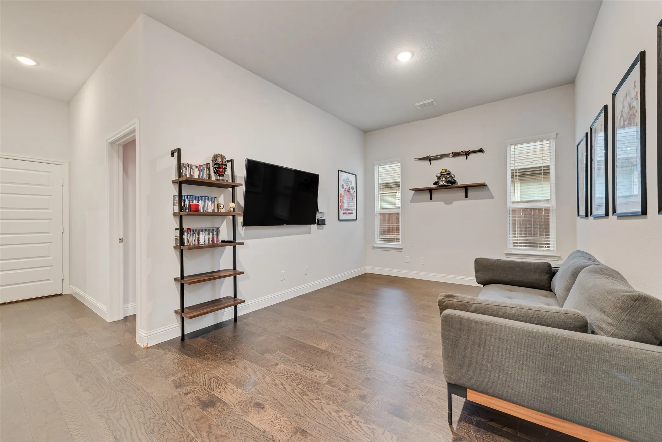 Wood-finish flooring, recessed lighting, white walls, multiple windows with blinds, and white trim throughout