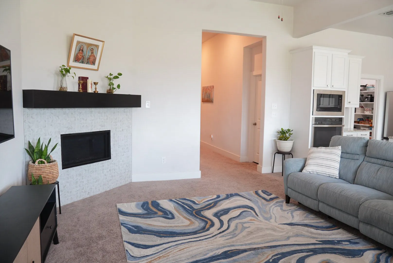 Corner fireplace with a dark mantel, built-in kitchen cabinetry, stainless steel microwave, and wall oven