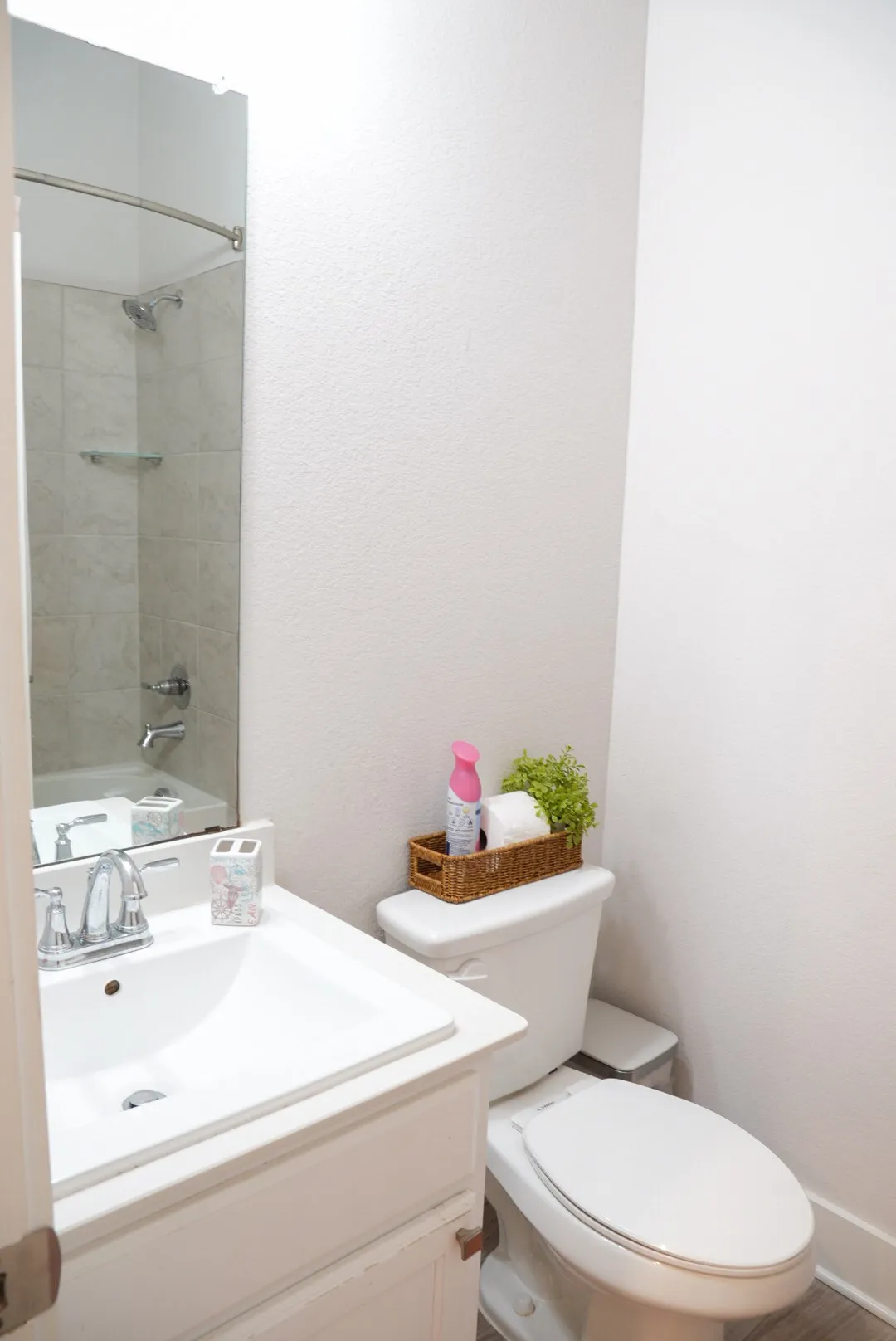 White vanity with integrated sink, chrome faucet, and rectangular mirror