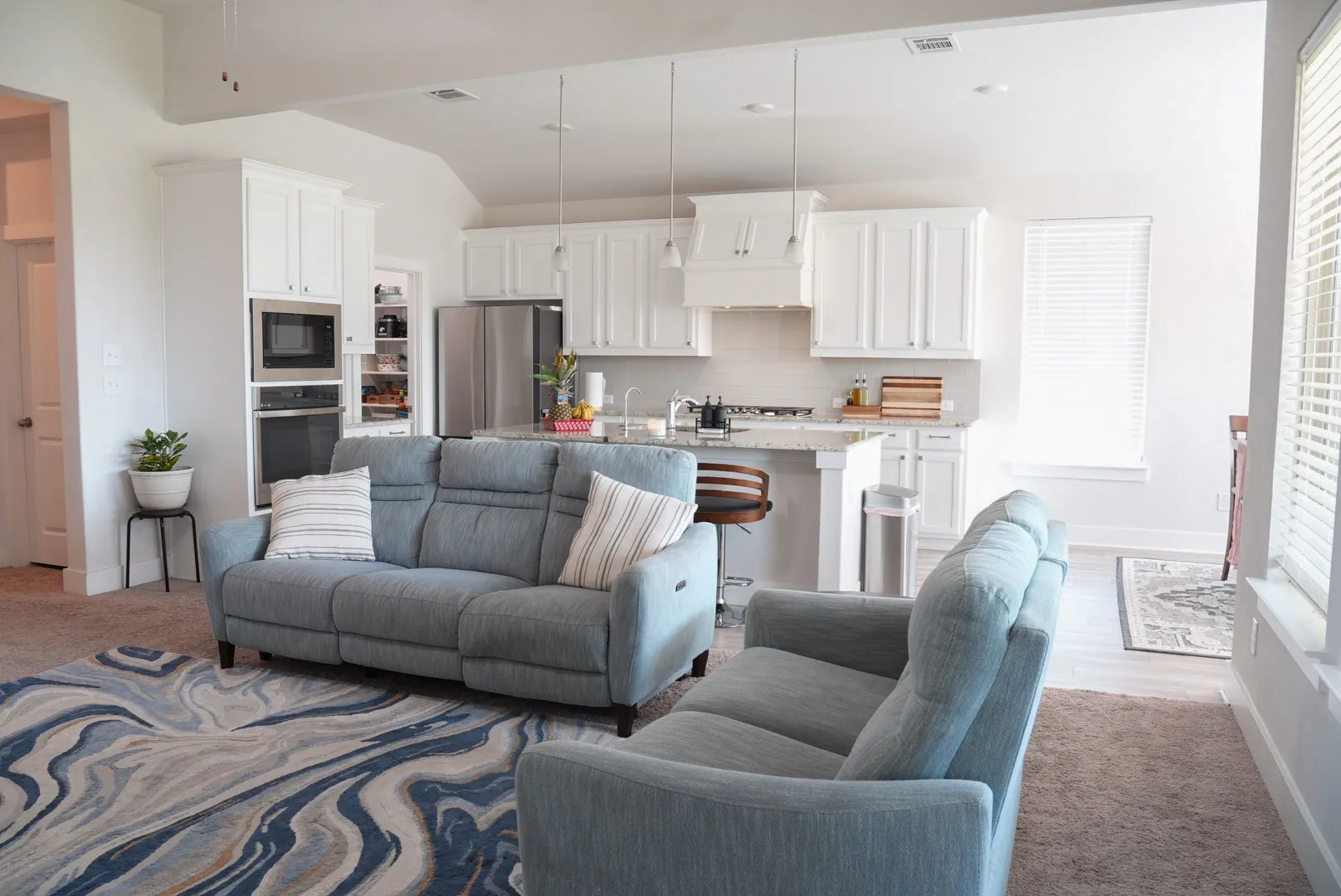 White kitchen cabinetry, stainless steel appliances, granite countertops, built-in microwave and oven, and recessed lighting
