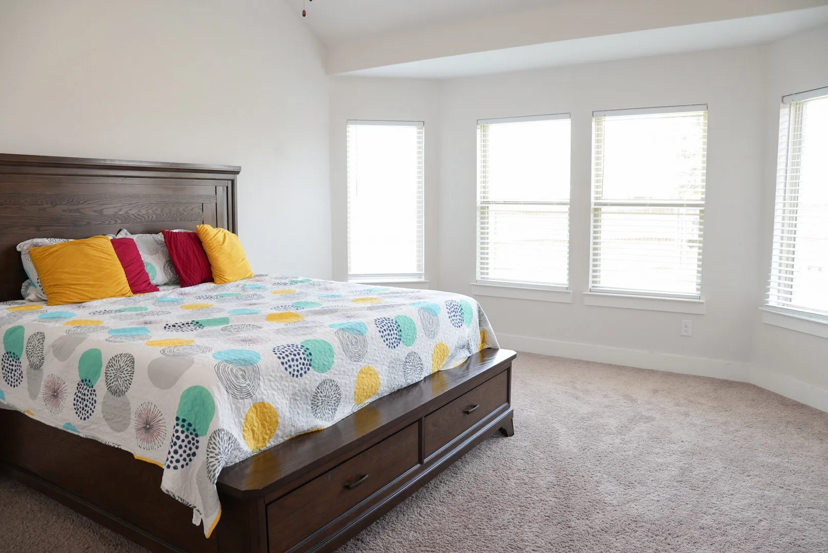 Vaulted ceiling with a ceiling fan, bay window with multiple windows, and carpet flooring