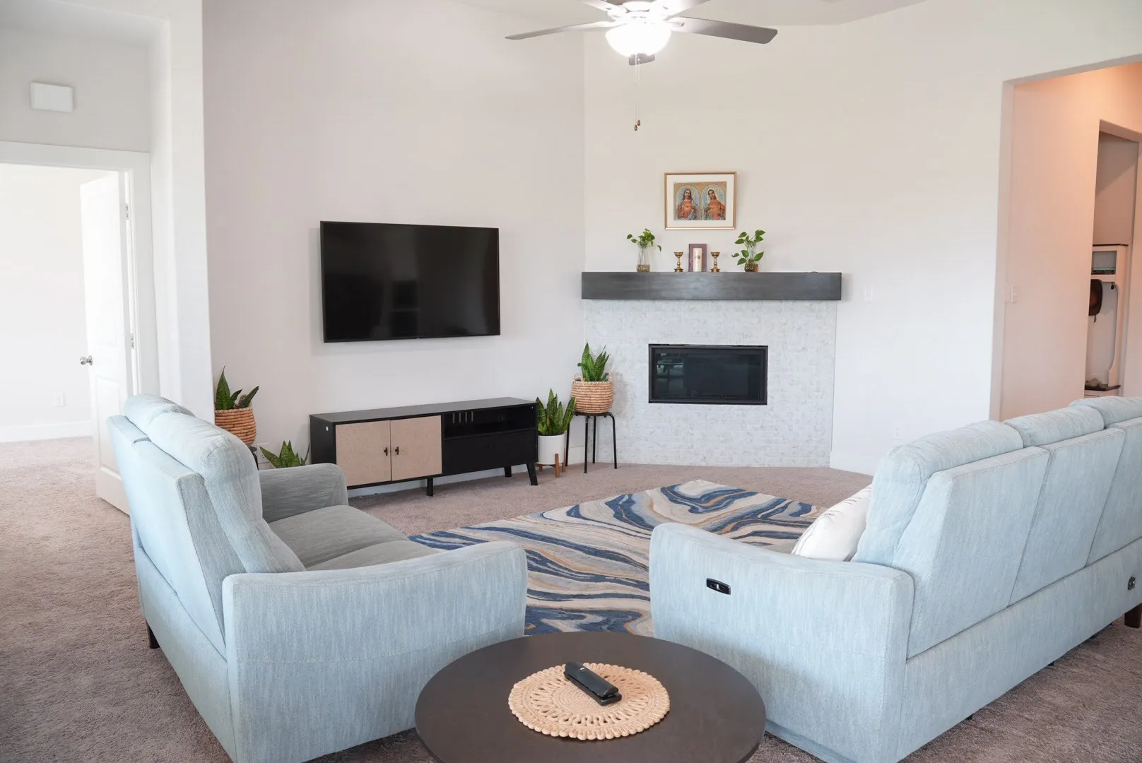 Vaulted ceiling with a ceiling fan, a fireplace with a dark mantel, and carpet flooring throughout