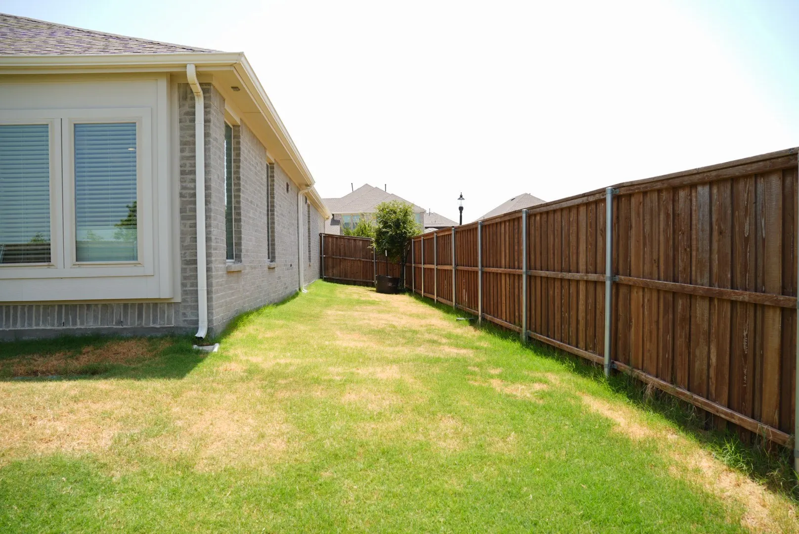 Brick exterior with multiple windows and a wood fence