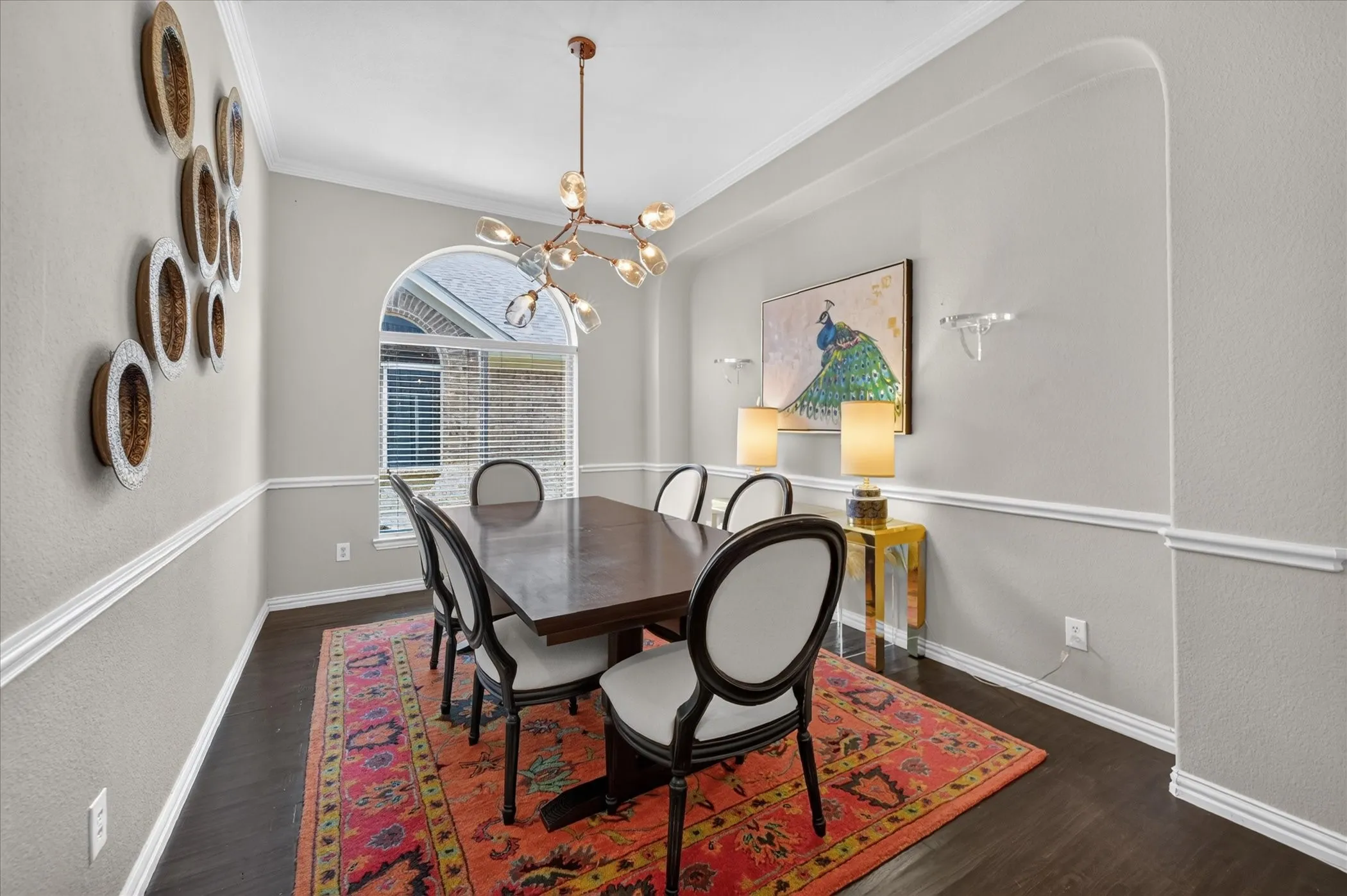 Elegant dining room featuring dark wood-finish flooring, high ceilings with crown molding, and a brass multi-arm pendant light fixture