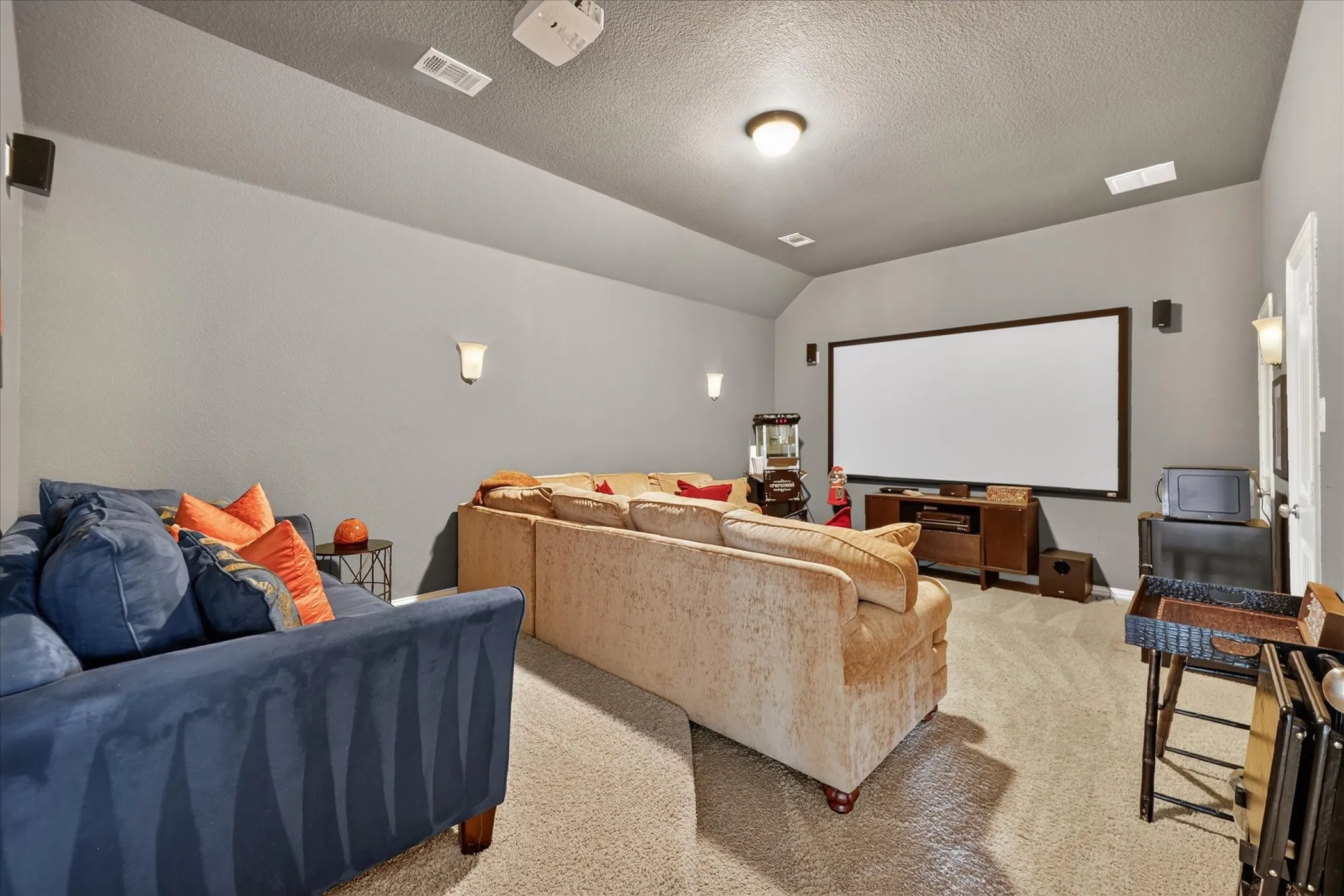 Vaulted ceiling, wall-mounted speakers, recessed lighting, wall sconces, large projection screen