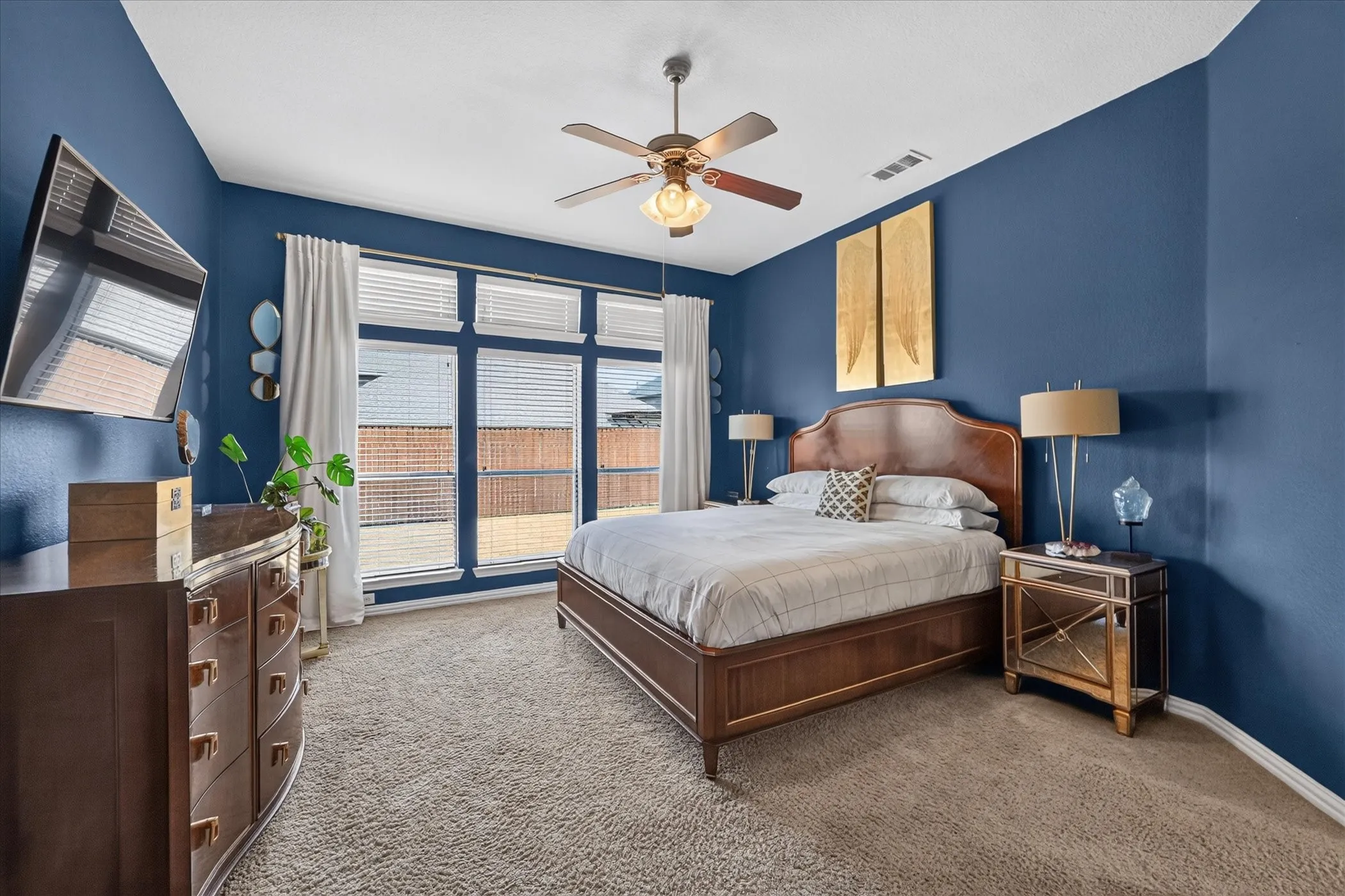 Spacious room featuring broad windows with blinds, a ceiling fan with integrated lighting, and carpet flooring