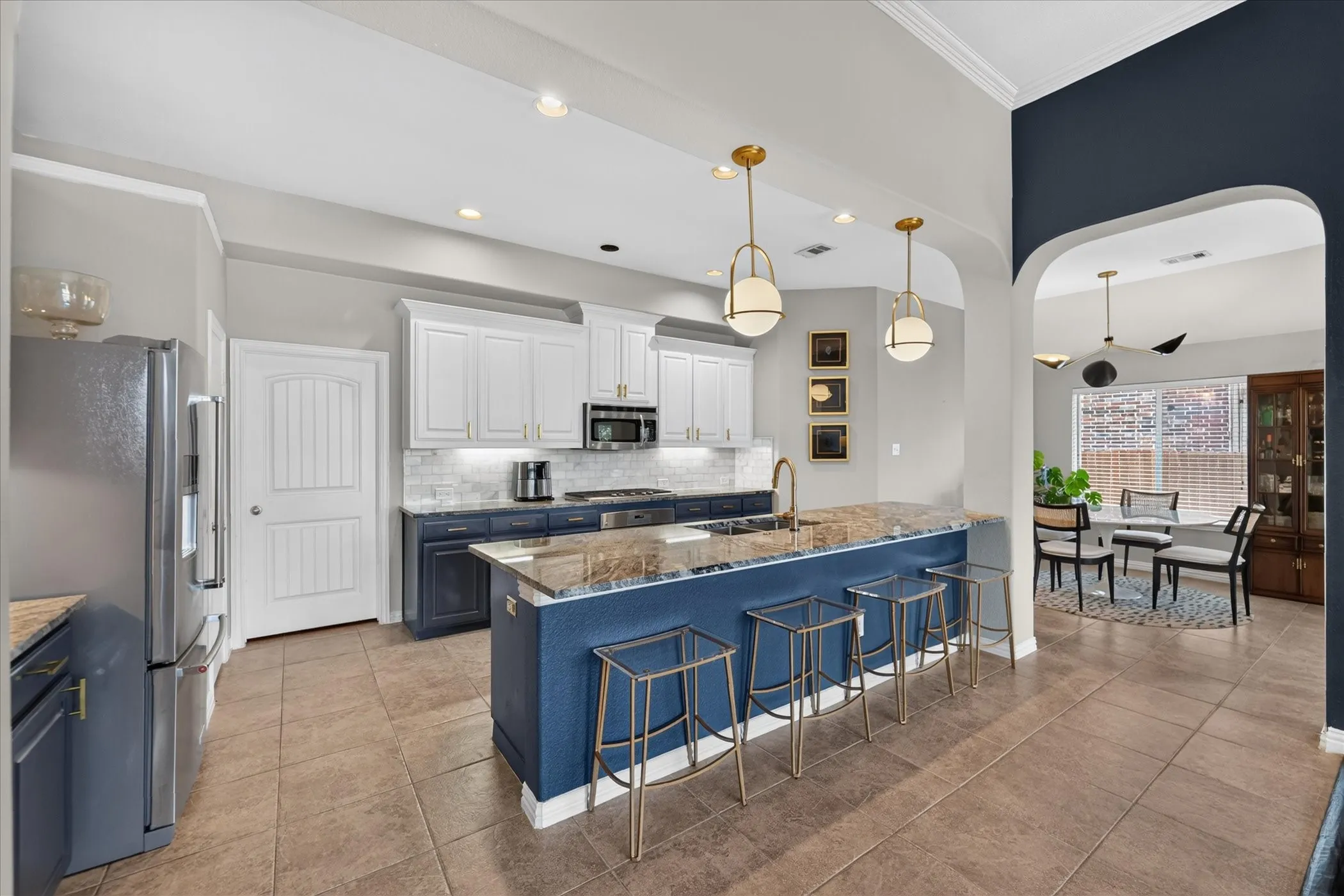 Modern kitchen featuring a large central island, stainless steel appliances, and tile flooring