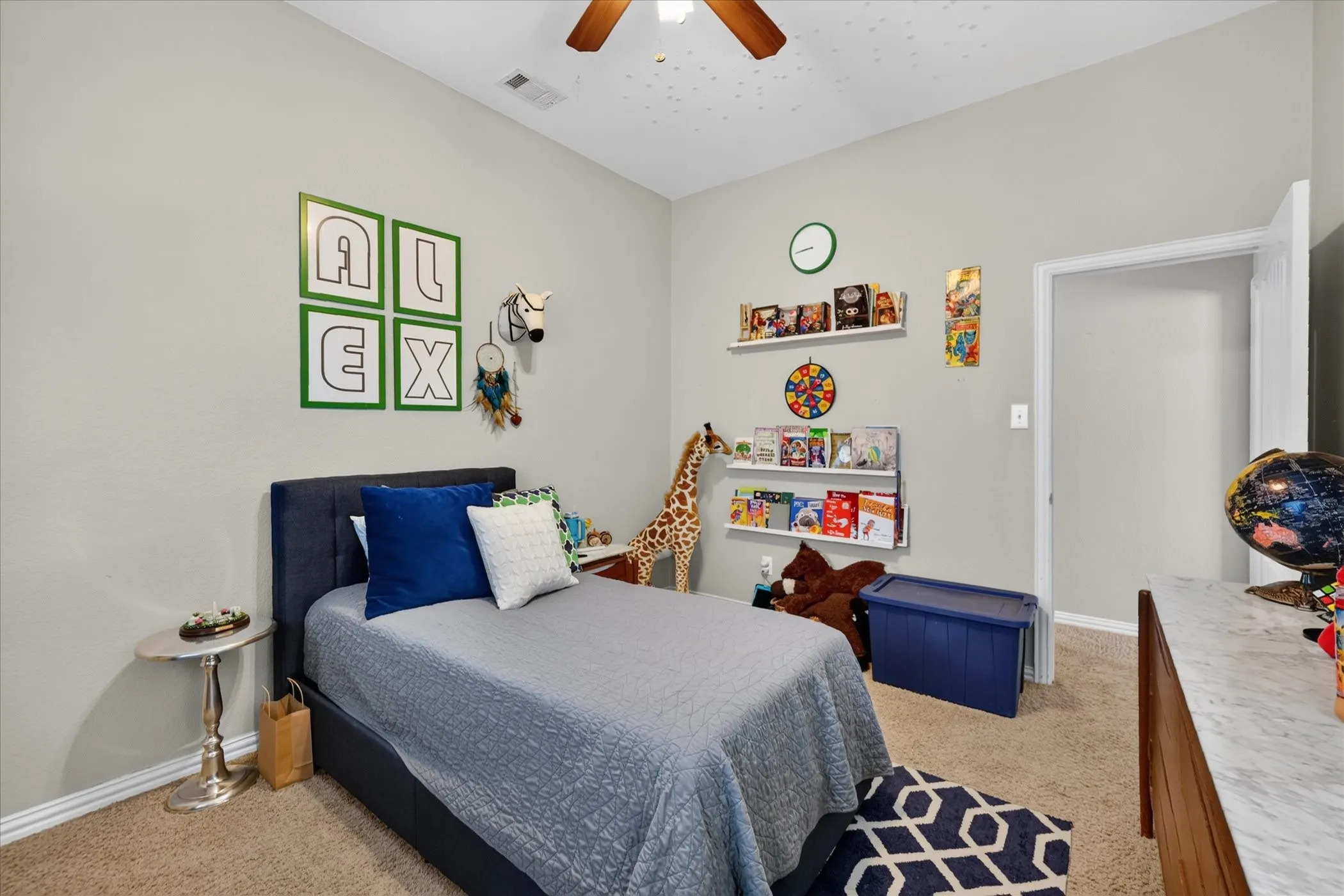 Carpeted flooring, light neutral wall color, ceiling fan, white trim, and built-in wall shelving