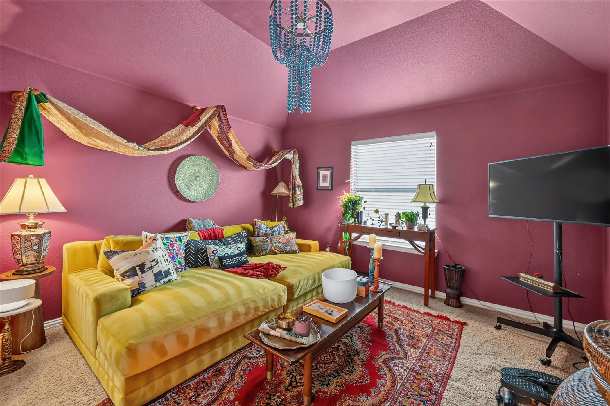 Vaulted ceiling with textured finish, window with blinds, and wall-mounted art