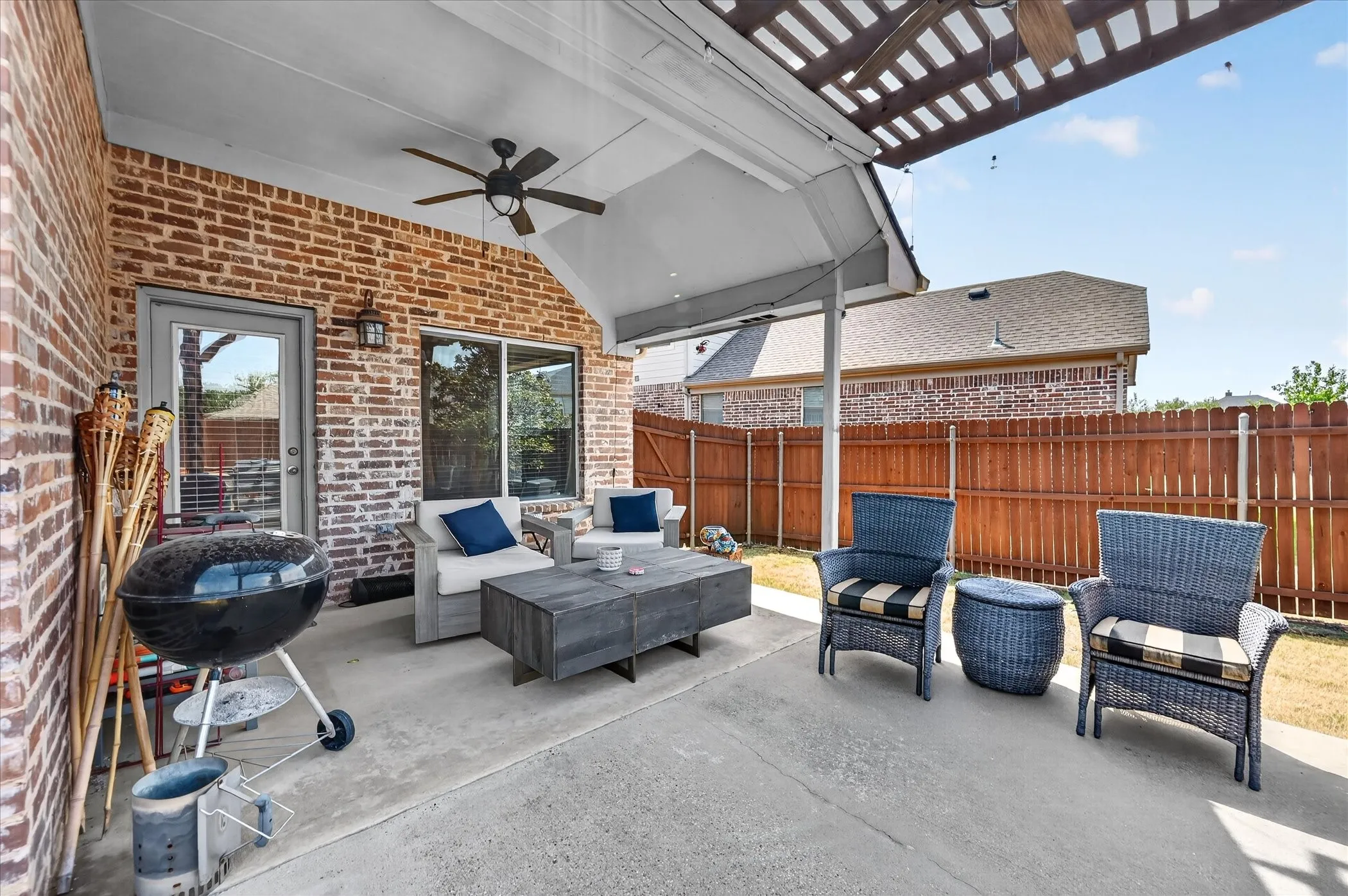 Covered patio with a ceiling fan, concrete flooring, and brick exterior wall