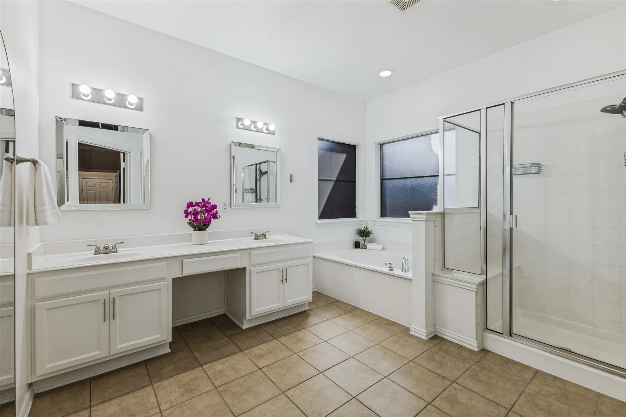 Modern ensuite bath with two vaniites, separate tub and glass shower
