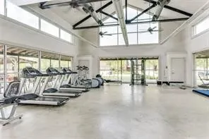 Vaulted ceiling with exposed beams, high transom windows, full-height windows, polished concrete flooring, and ceiling fans