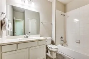 Spa-inspired bathroom featuring dual-sink vanity with ample storage, large framed mirror with integrated lighting, ceramic tile surround, and an alcove bathtub with shower combination and tile surround
