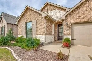 Brick and stone exterior featuring an arched entry, an attached garage, and a concrete walkway