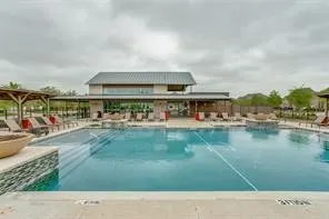 Swimming pool with integrated steps, surrounded by concrete decking and a stone-clad raised feature
