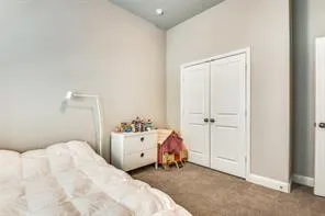 Carpeted flooring with painted walls, a flat ceiling, and bi-fold doors