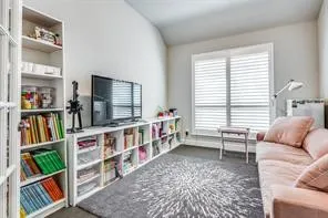 White built-in shelving, large window with horizontal blinds, and a neutral wall color