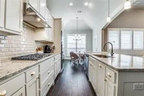 Kitchen featuring light cabinetry, a gas range with range hood, subway tile backsplash, and granite countertops