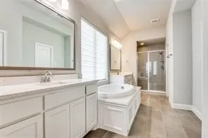 Spa-inspired primary bathroom featuring a generous layout with dual vanity and vessel sink, extensive countertop space, wood-finish flooring, a soaking tub with surround, and a walk-in shower with frameless glass enclosure and tile surround