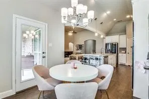 Wood-finish flooring, a contemporary chandelier, a glass-paneled exterior door, and a vaulted ceiling with recessed lighting