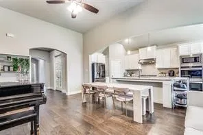 Vaulted ceilings with a ceiling fan, recessed lighting, wood-finish flooring, white cabinetry, and stainless steel appliances