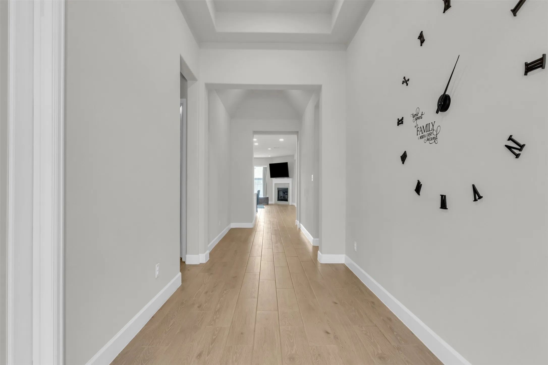 Hall with light wood finished floors and a tray ceiling