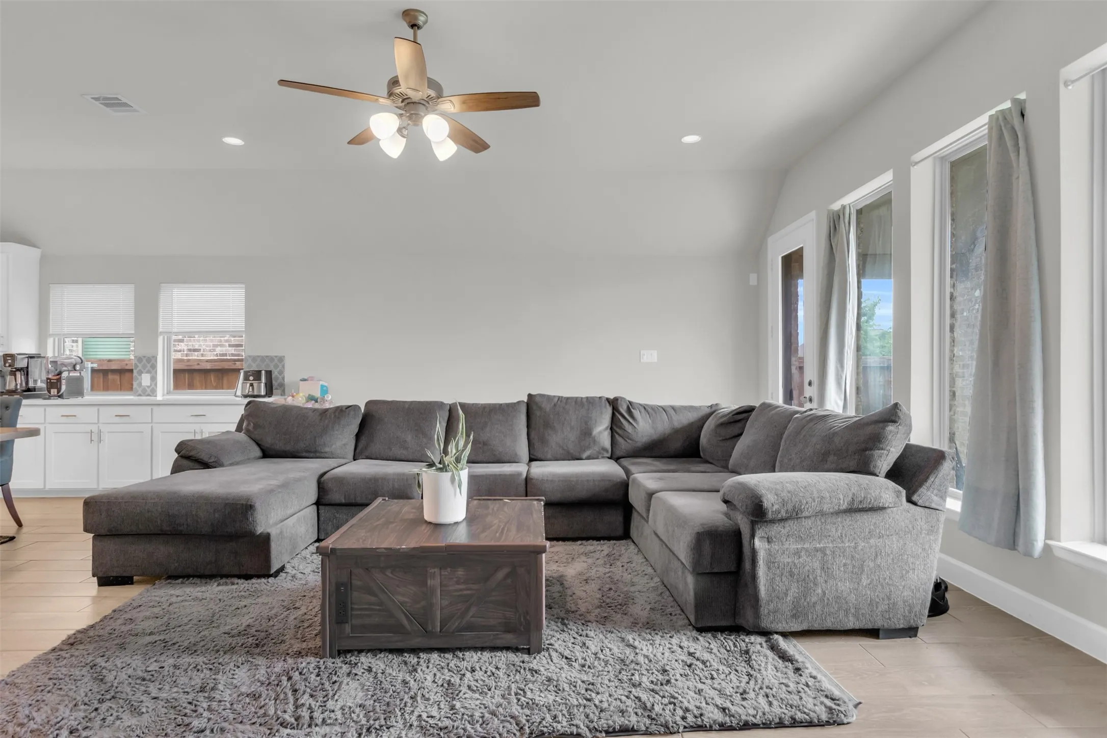 Living room with plenty of natural light, a ceiling fan, recessed lighting, light wood-type flooring, and lofted ceiling