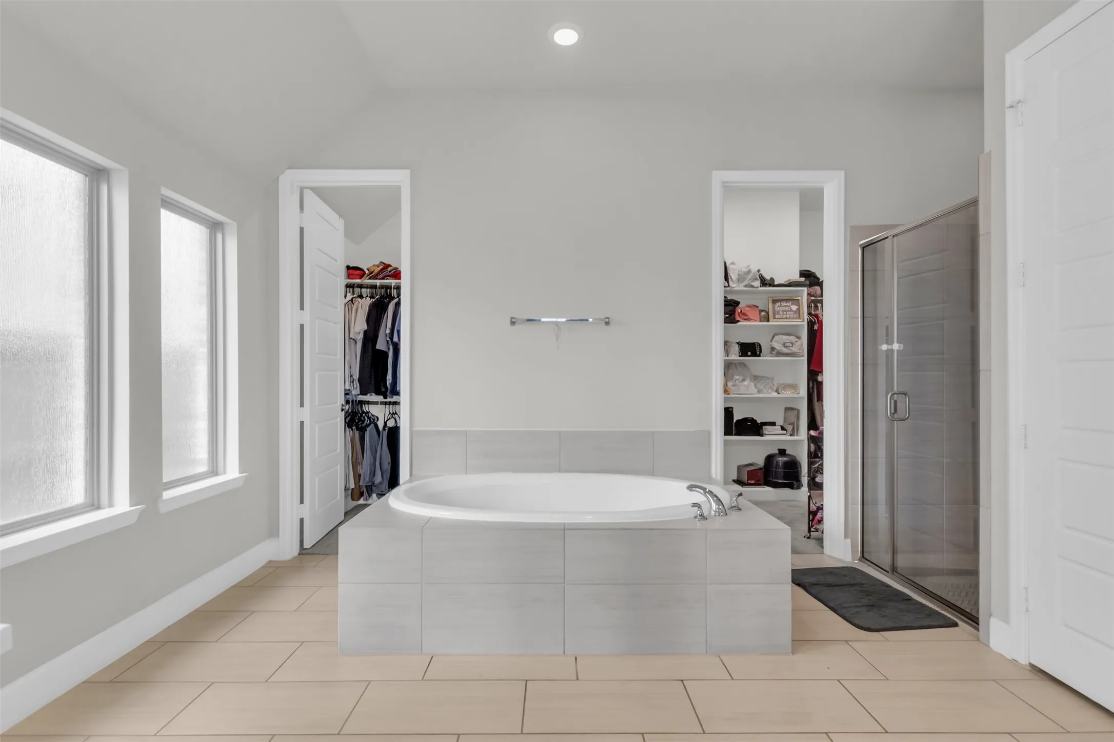 Bathroom featuring a spacious closet, a shower stall, a garden tub, vaulted ceiling, and recessed lighting