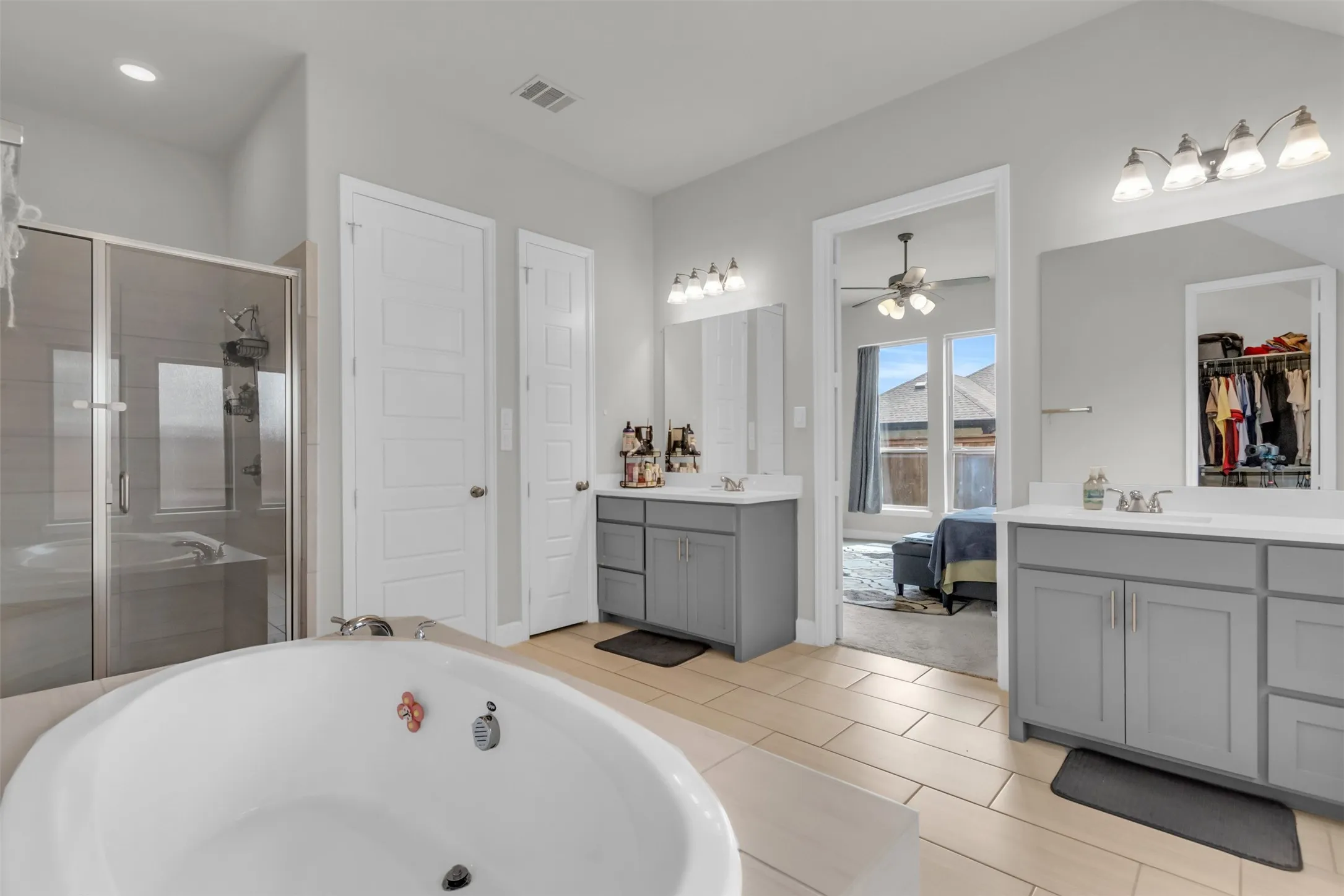 Full bathroom featuring a shower stall, two vanities, and a garden tub