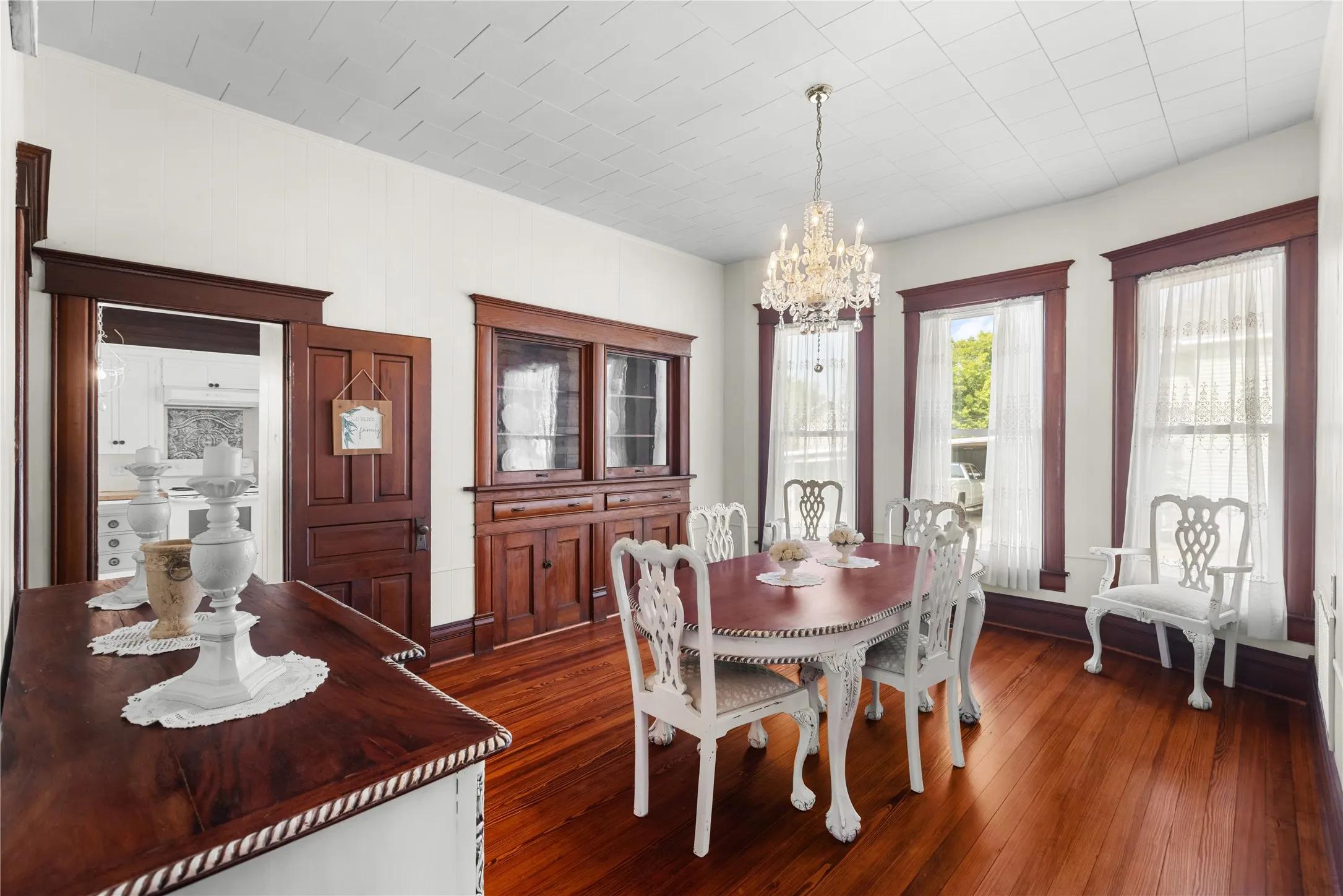Hardwood flooring, ornate wood trim, built-in wooden cabinetry, chandelier, and a decorative ceiling