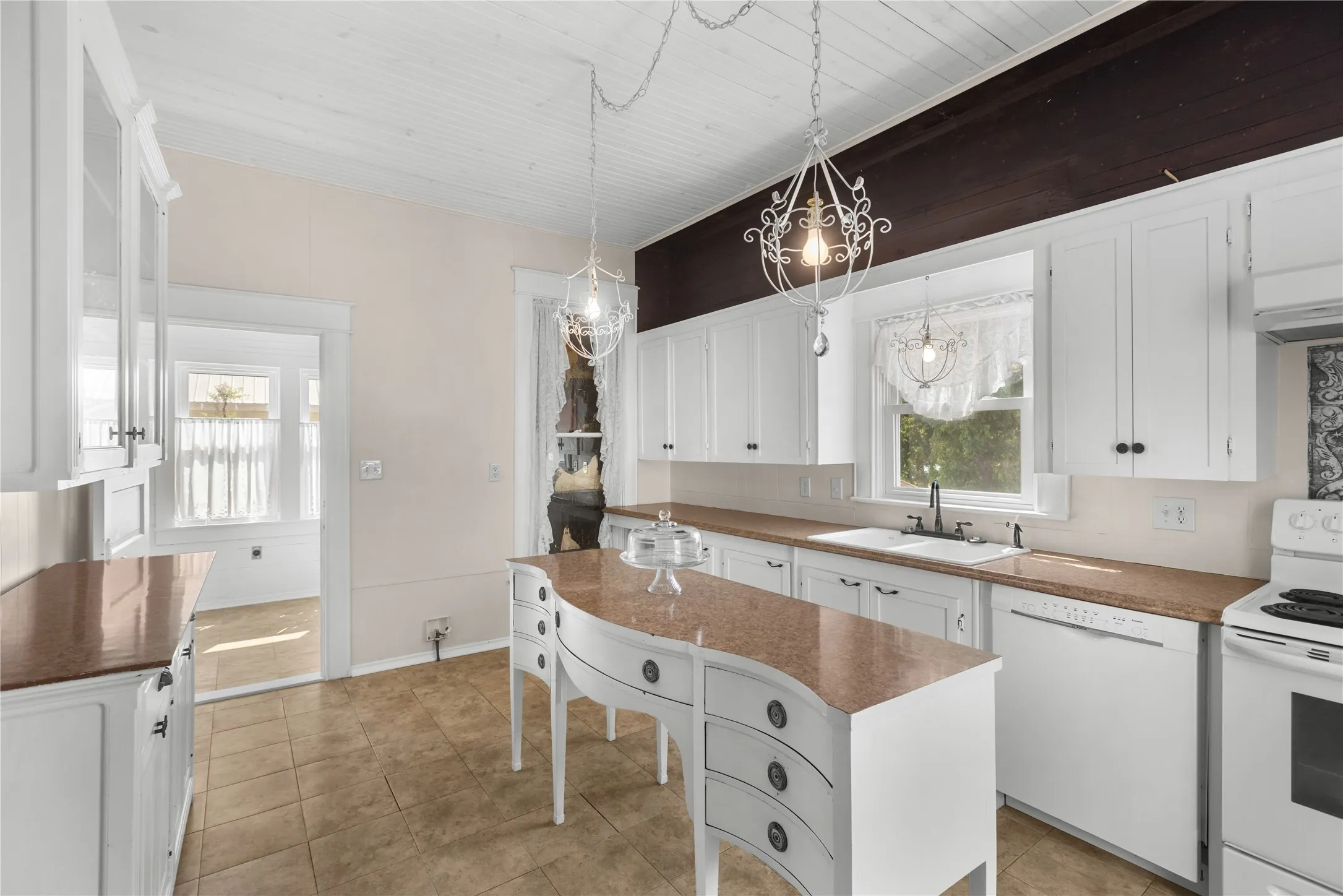 White cabinetry with black hardware, brown countertops, and tile flooring