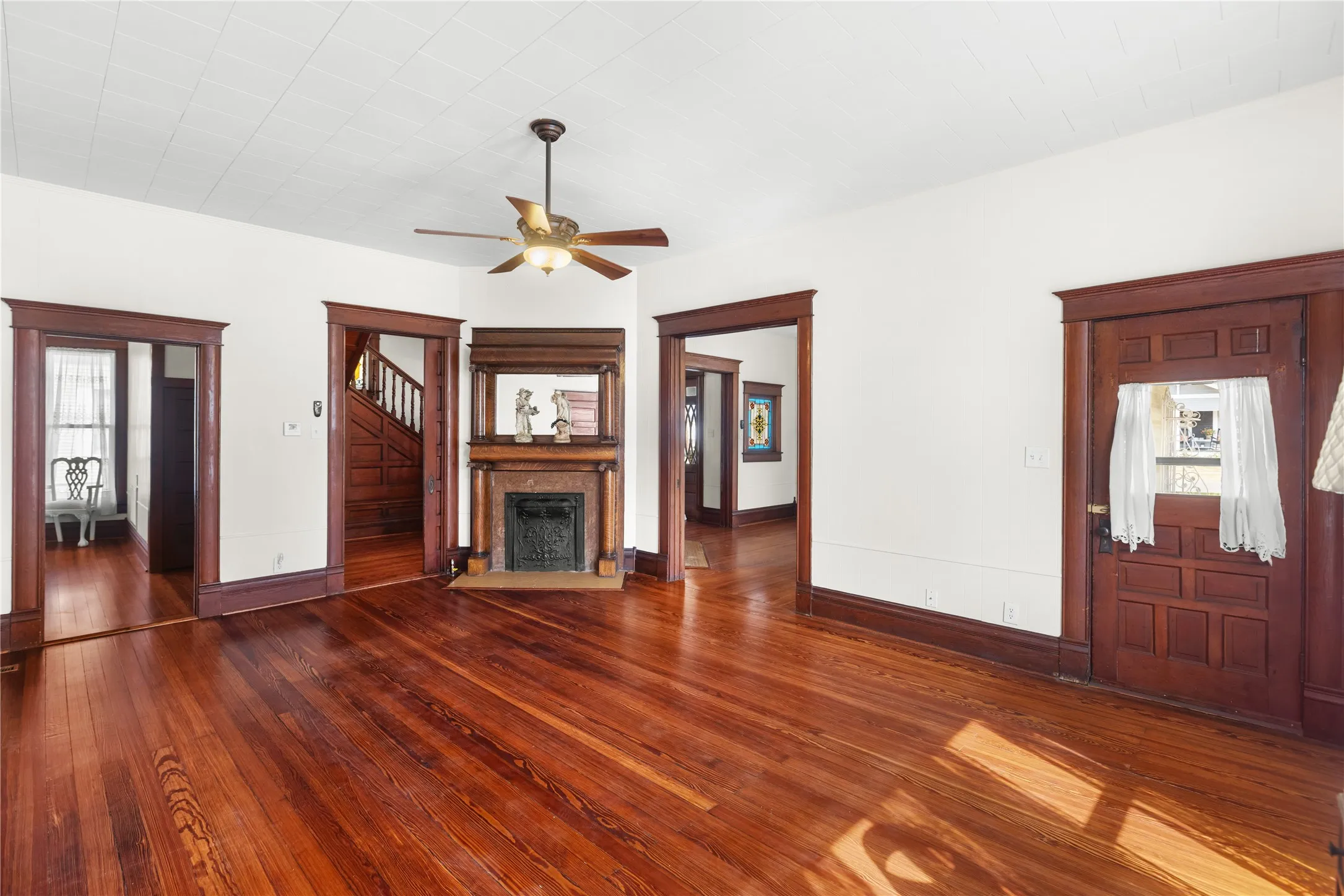 Hardwood flooring, wood-framed doorways, and a decorative fireplace with a mantel