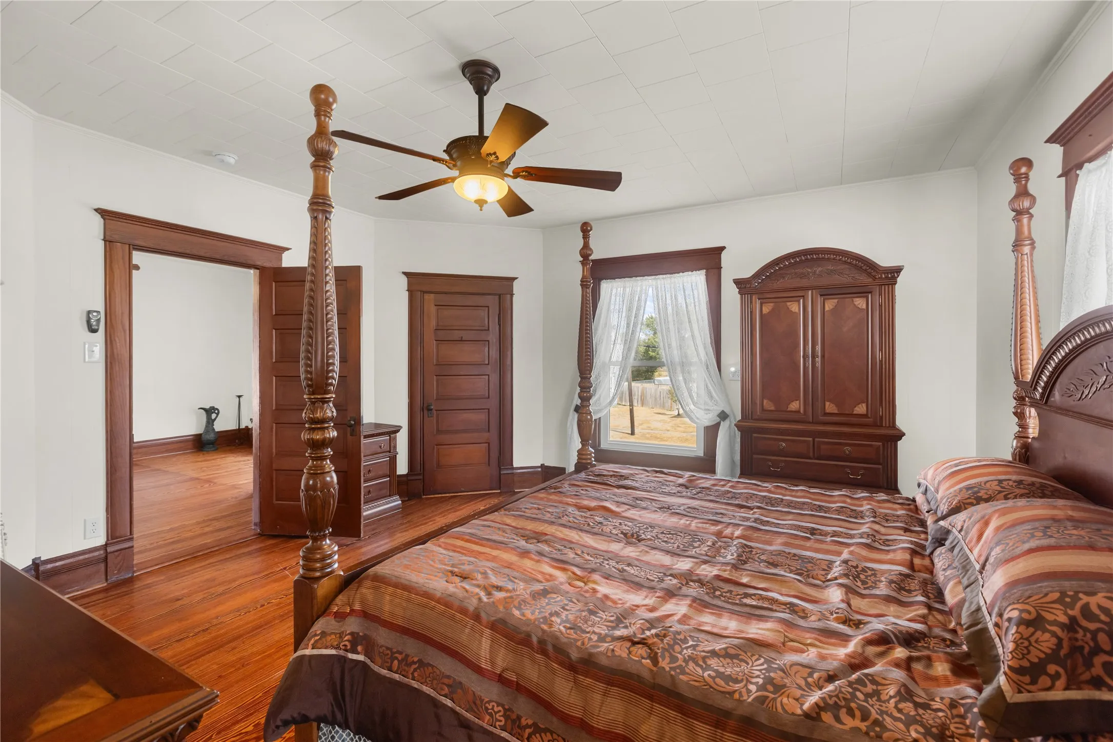 Wood-finish flooring throughout, detailed wood trim, wood-paneled doors, and a ceiling fan with integrated lighting