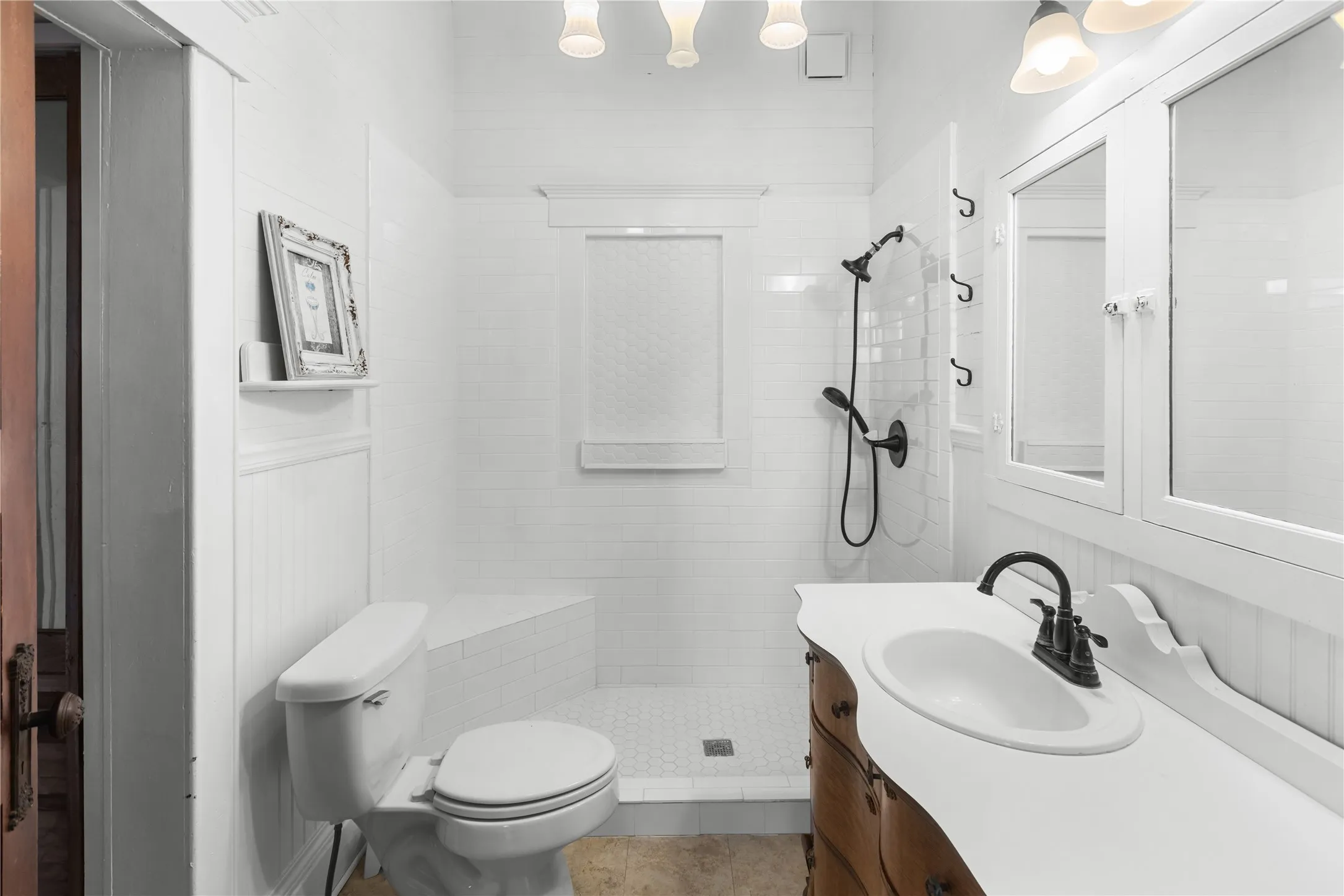 Shower with bench seating, subway tile surround, curved vanity with integrated sink, and wall-mounted medicine cabinet