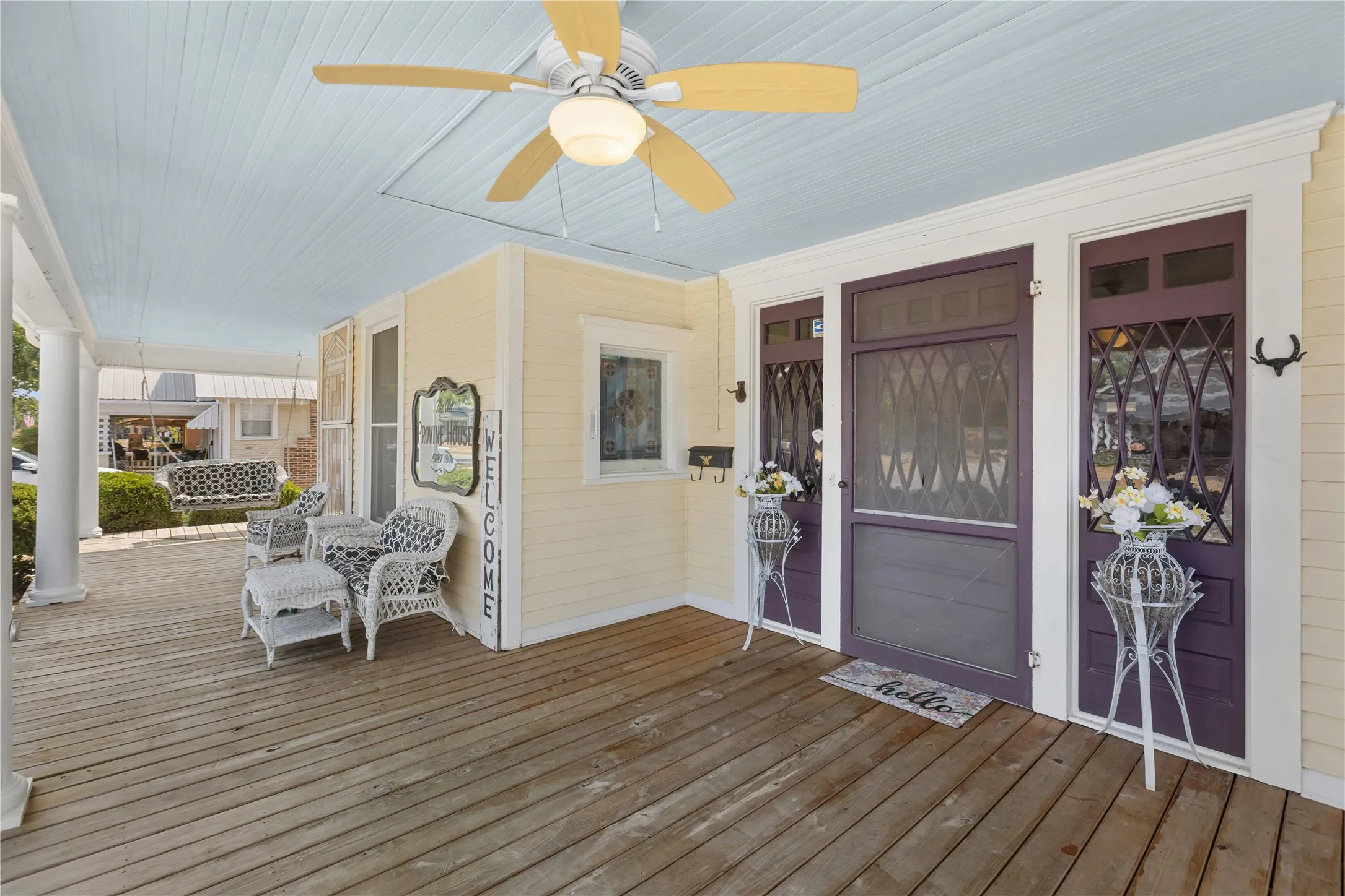 Expansive covered porch with wood flooring, ceiling fan, and decorative porch columns