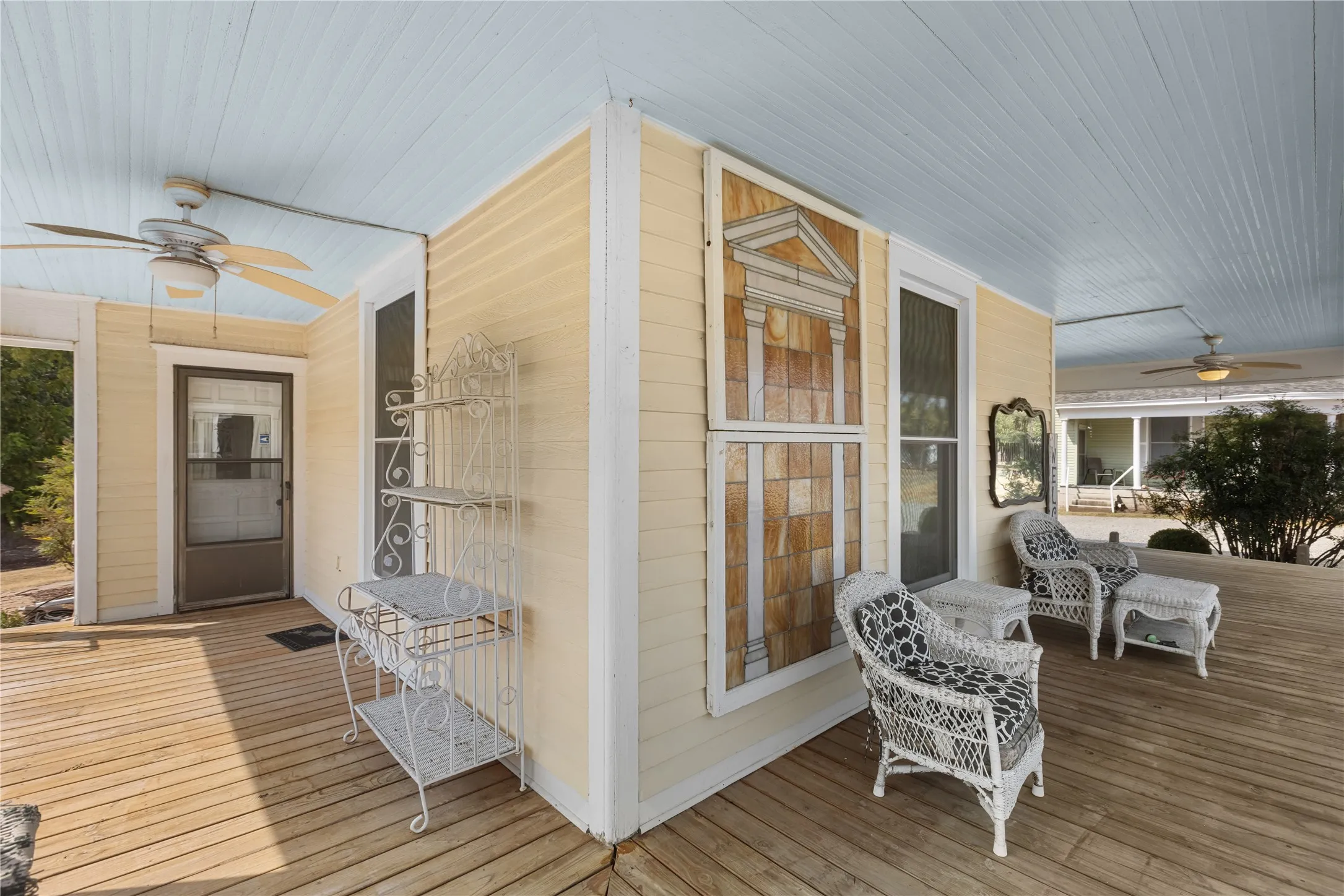 Expansive covered porch with wood flooring, ceiling fans, and a light blue beadboard ceiling